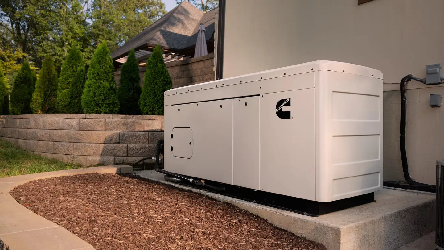 Cummins liquid-cooled home standby generator on a pad beside a large home